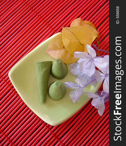 Green incense on a dish with flowers. Green incense on a dish with flowers