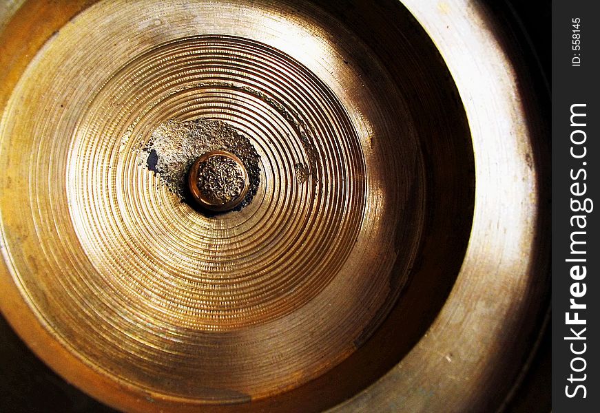 Close-up of a brass or bronze wheel or disk showing ribbing and texture as well as deep light and shadow. Close-up of a brass or bronze wheel or disk showing ribbing and texture as well as deep light and shadow.