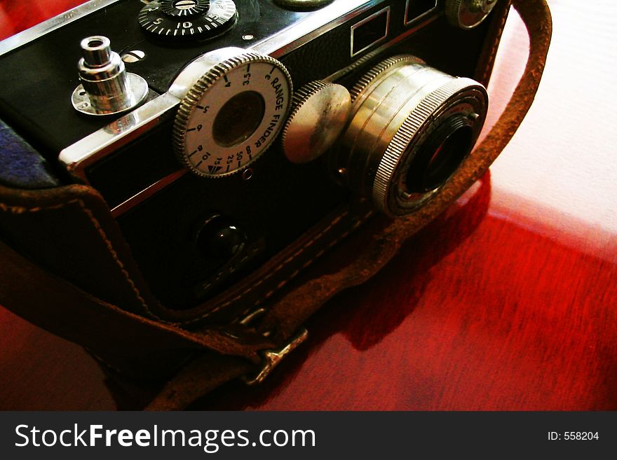 Vintage rangefinder camera ca. 1939 on deep red cherry wood desk in soft or mood focus. Vintage rangefinder camera ca. 1939 on deep red cherry wood desk in soft or mood focus.