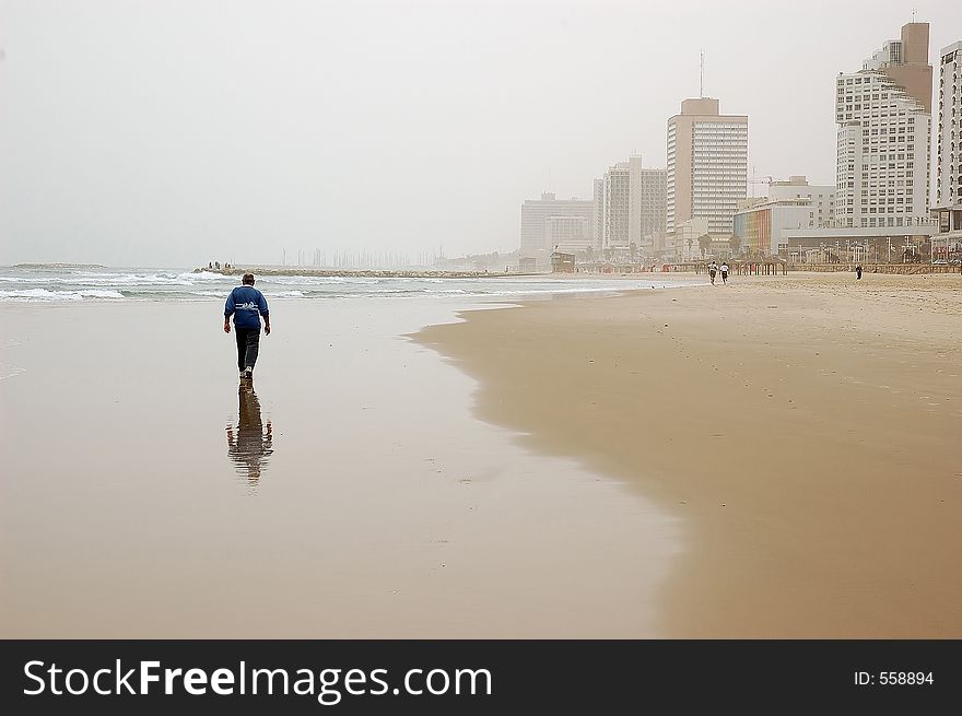 Elderly man enjoying a walk on empty winter beach in bad weather. Elderly man enjoying a walk on empty winter beach in bad weather
