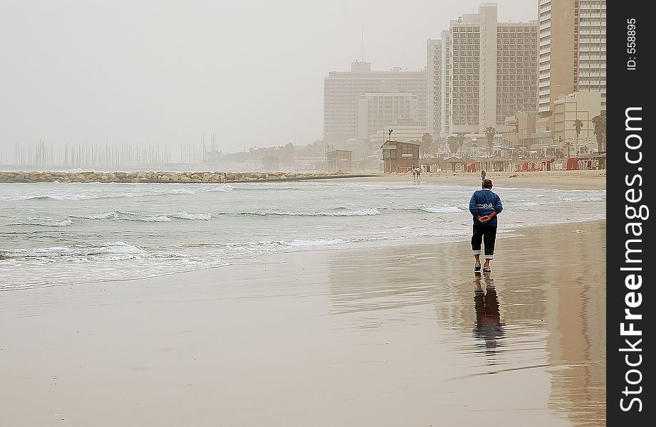 Elderly man enjoying a walk on empty winter beach in bad weather. Elderly man enjoying a walk on empty winter beach in bad weather