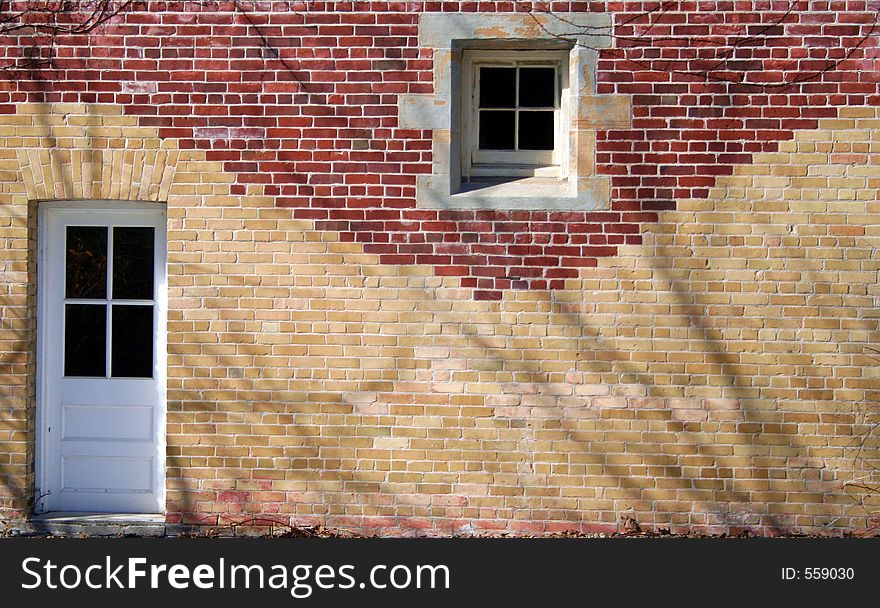 A door and window in a red and tan brick wall