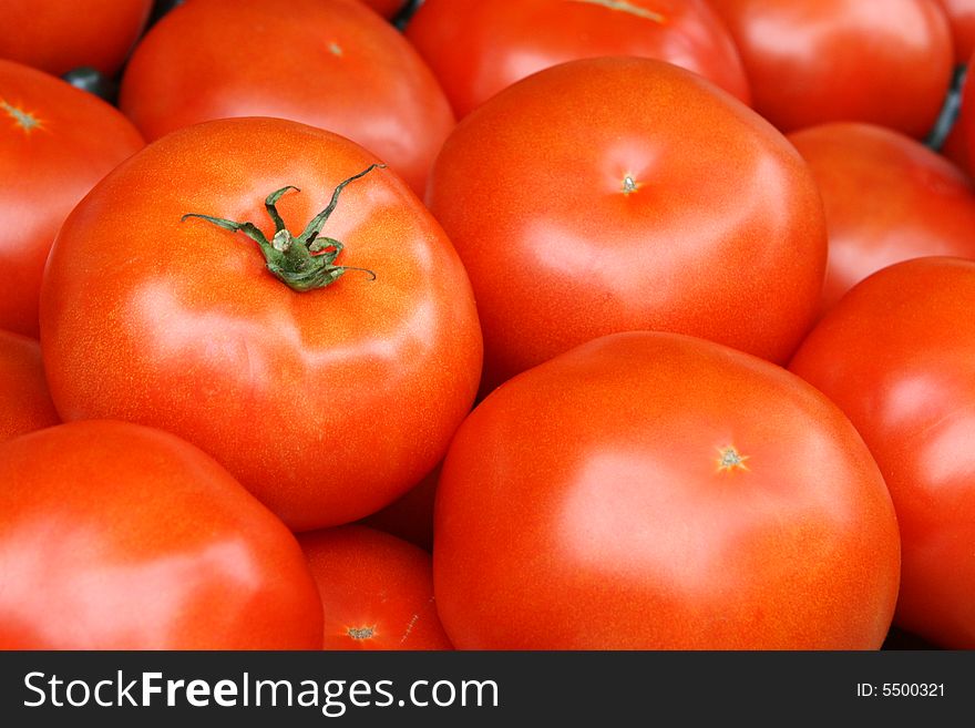 Fresh picked tomato with stem surrounded by other tomatoes. Fresh picked tomato with stem surrounded by other tomatoes