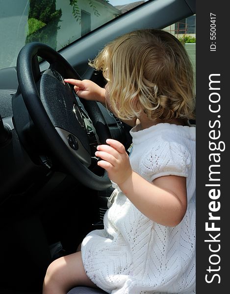 Little girl sits in a car and plays with the steering wheel, pretending to drive. Little girl sits in a car and plays with the steering wheel, pretending to drive.