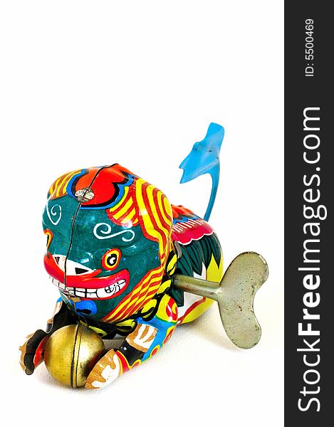 Wind-up toy dragon from China with blue tail and a golden ball in its paws, made of brightly-painted metal.  The winding key is visible in its side. Wind-up toy dragon from China with blue tail and a golden ball in its paws, made of brightly-painted metal.  The winding key is visible in its side.