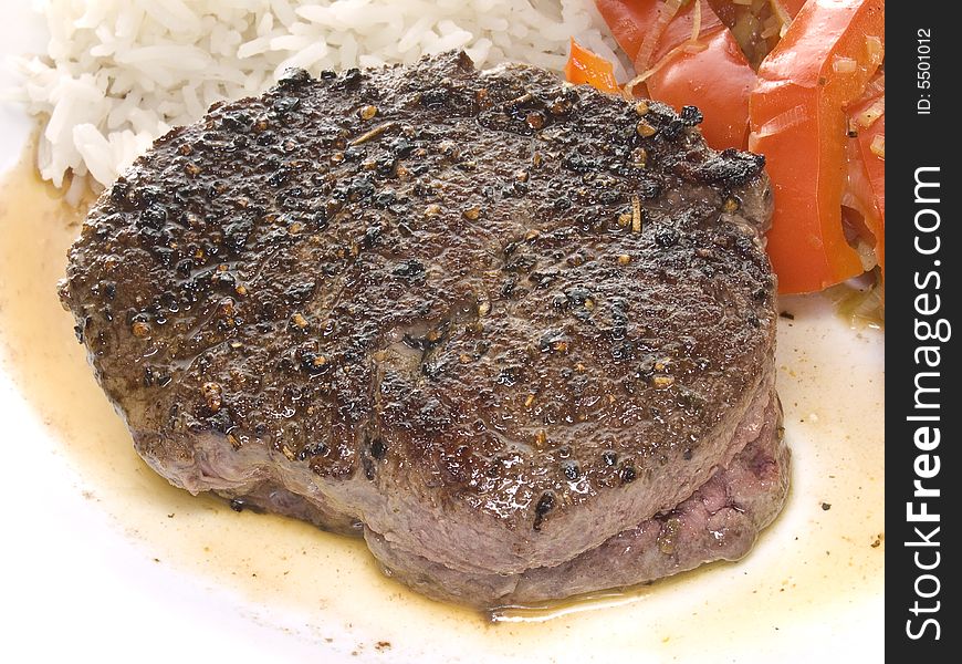 Fried beef steak served with paprika and plain rice on a white plate. Fried beef steak served with paprika and plain rice on a white plate