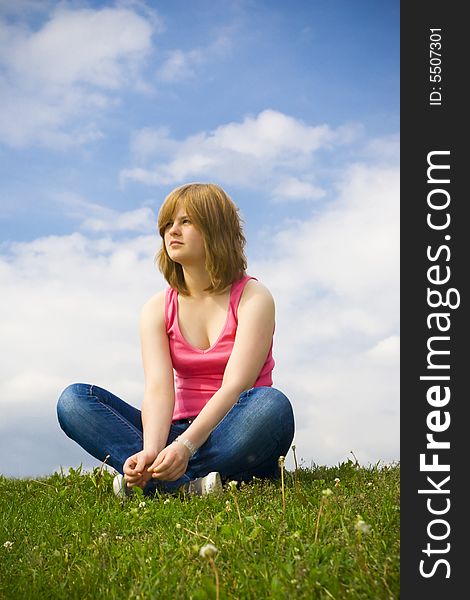 The Young Girl Sitting On A Green Grass