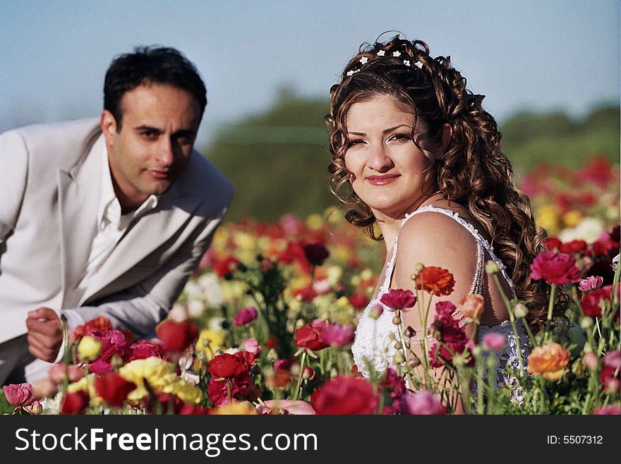 Groom and bride in the flower field holding flowers