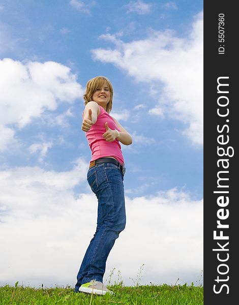 The young attractive girl standing on a green grass