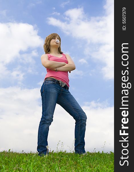 The young attractive girl standing on a green grass