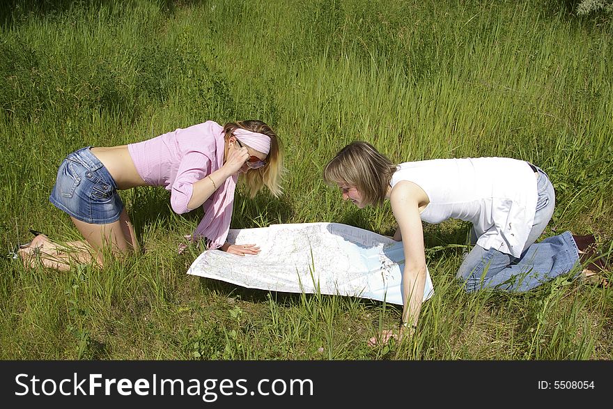 Two beautiful girls looks at the map on nature. Two beautiful girls looks at the map on nature