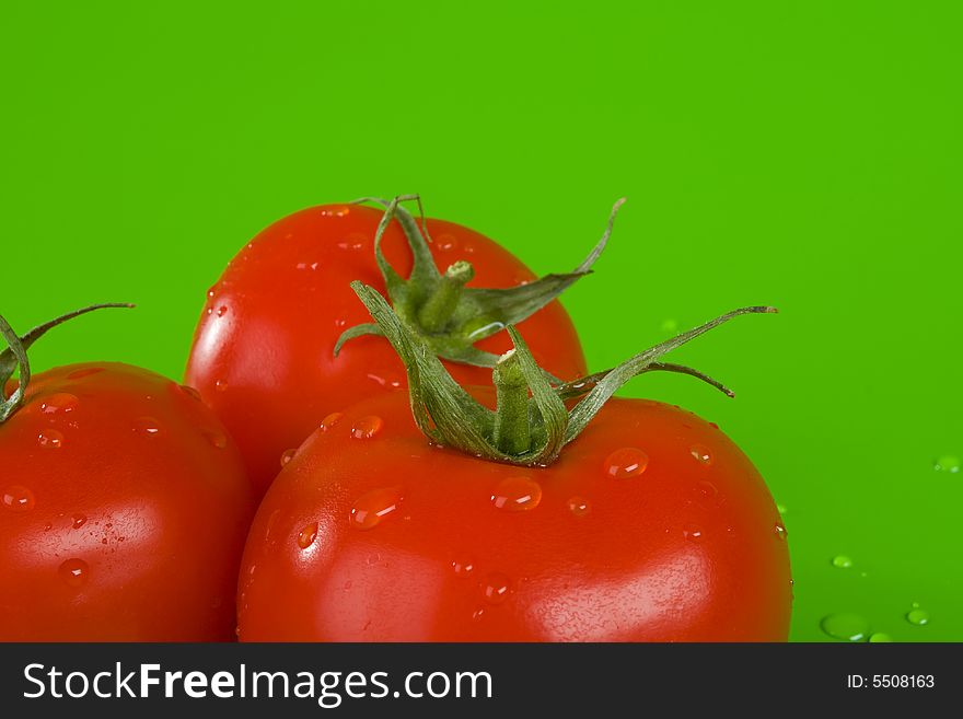 Three tomatoes on green, drops