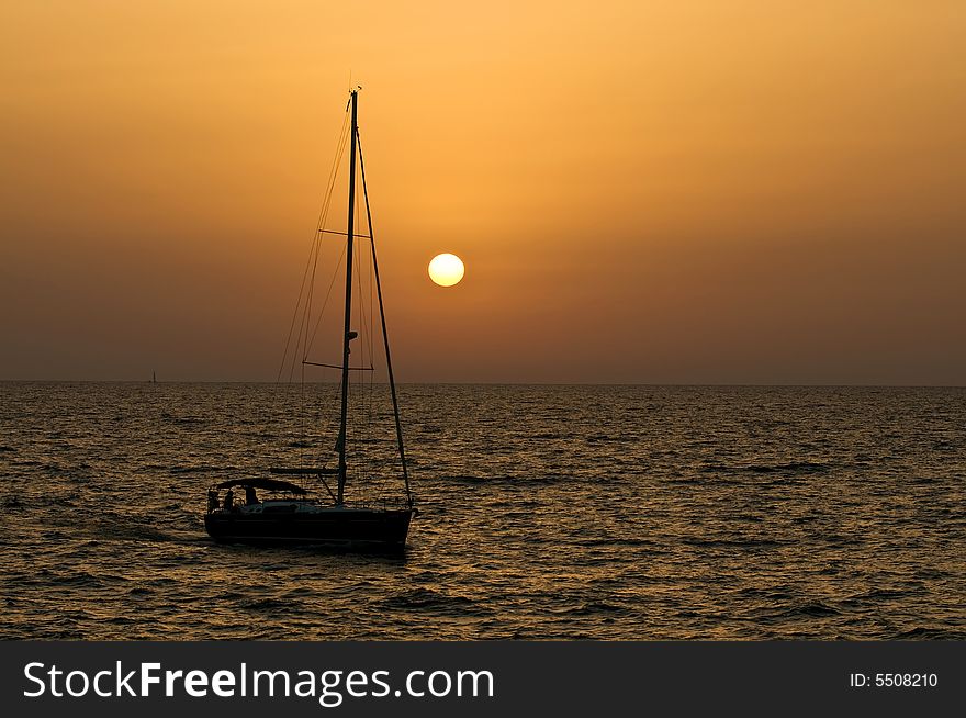 Yacht sailing into beautiful orange sunset. Yacht sailing into beautiful orange sunset