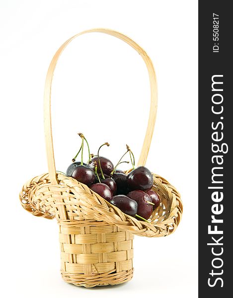 Small straw basket of cherries isolated on white background