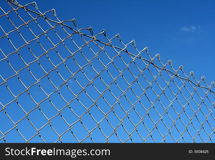 A chain link fence in front of a blue sky.