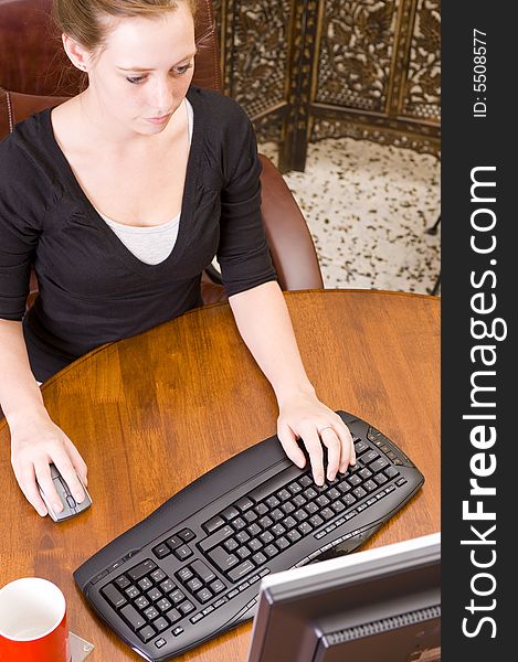 Woman working on PC keyboard and mouse.