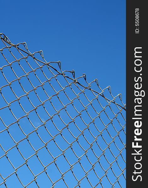 A chain link fence in front of a blue sky.