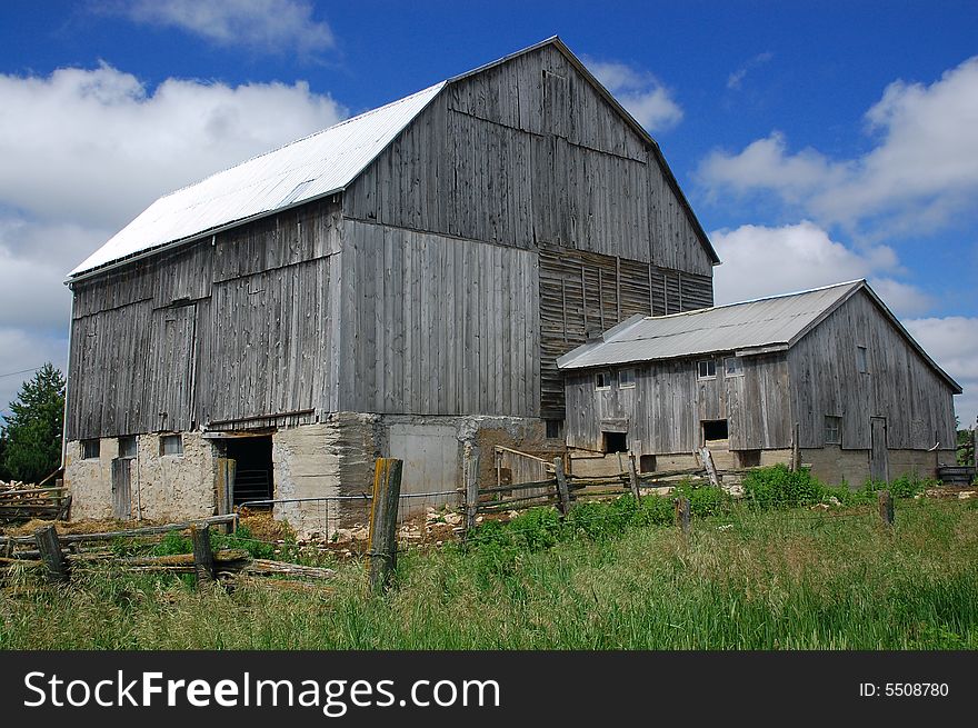 A view of a barn with clouds and blue sky in the background. A view of a barn with clouds and blue sky in the background