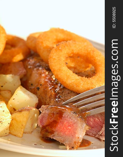 Juicy seared New York Cut strip steak with onion rings and potatoes