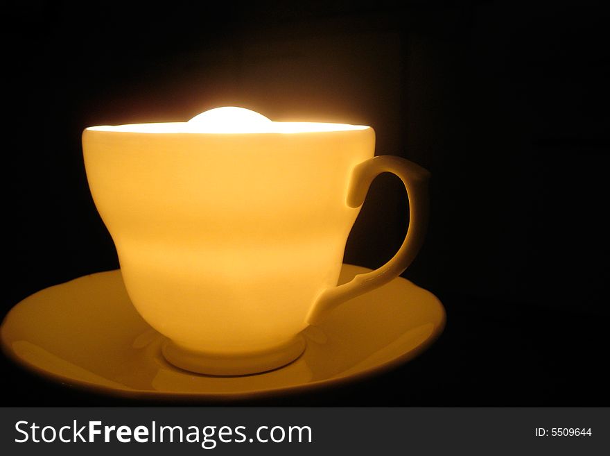 A cup with light in it, very close up angle view. dark background. A cup with light in it, very close up angle view. dark background.