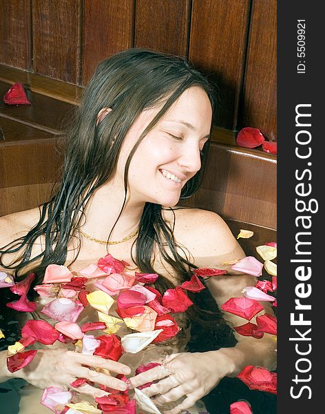 Woman relaxes in a spa tub filled with rose petals. She is closing her eyes and looks happy and relaxed. Woman relaxes in a spa tub filled with rose petals. She is closing her eyes and looks happy and relaxed.