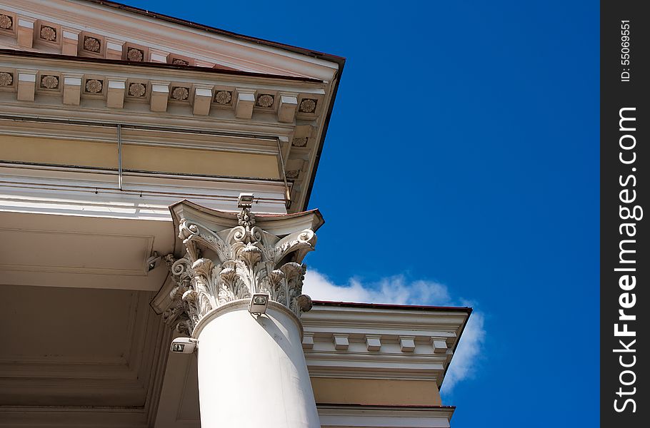 White column and a fragment of the roof of the old building. bottom view, detail