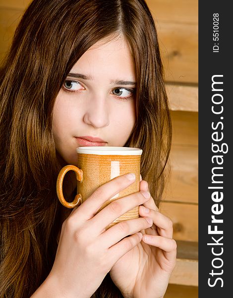 Portrait of the dark-haired girl with a mug close up  a wooden ladder background. Portrait of the dark-haired girl with a mug close up  a wooden ladder background