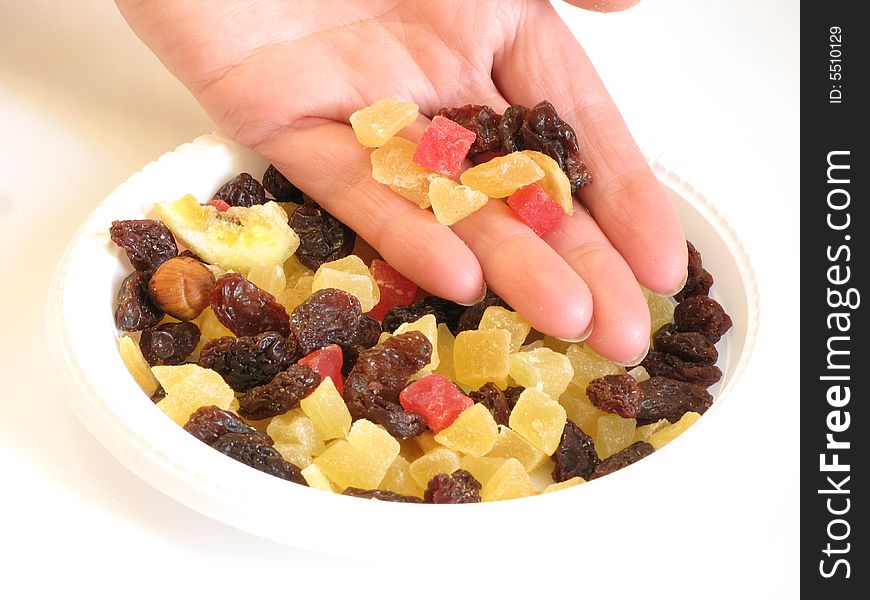 Candied peel, raisins, and women's hand.food on a plate