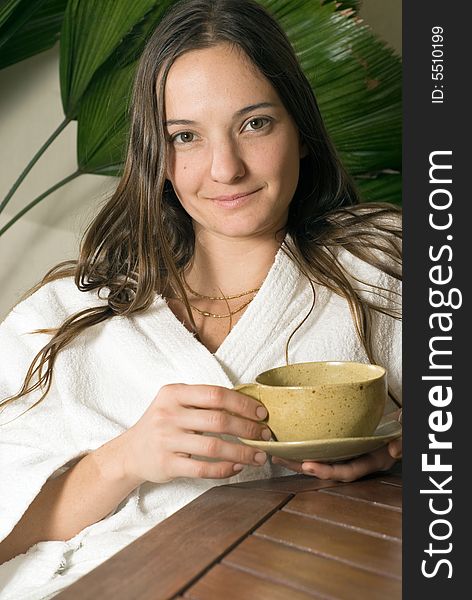 Woman Relaxes while she holds a tea cup in her hand. Vertically framed photograph. Woman Relaxes while she holds a tea cup in her hand. Vertically framed photograph.