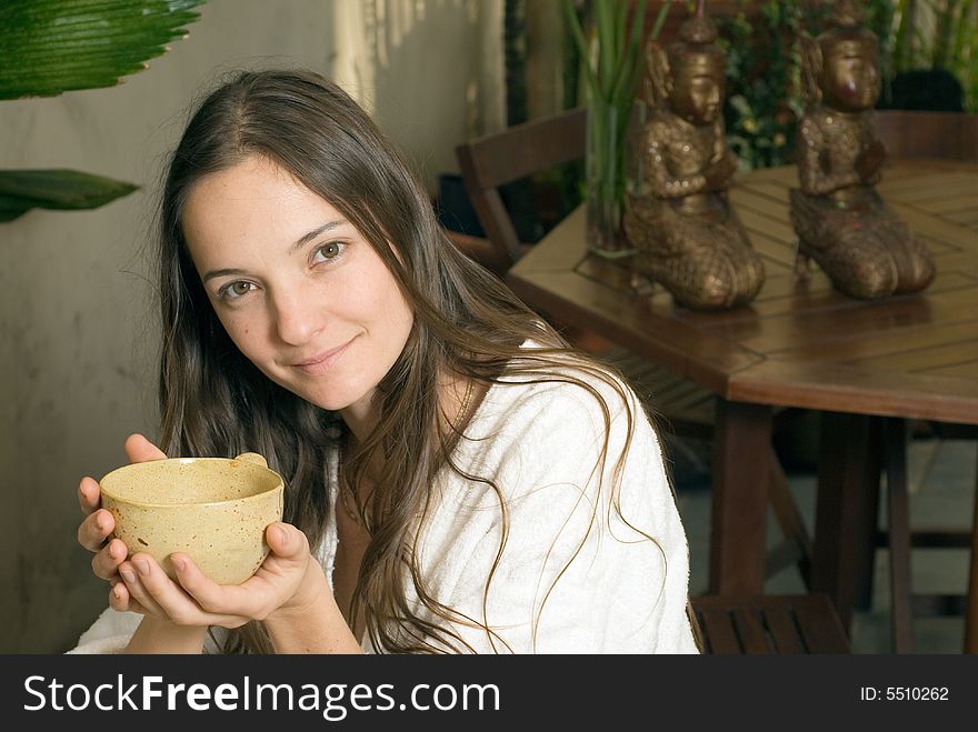 Woman smiles as she holds a tea cup. Horizontally framed photograph. Woman smiles as she holds a tea cup. Horizontally framed photograph.