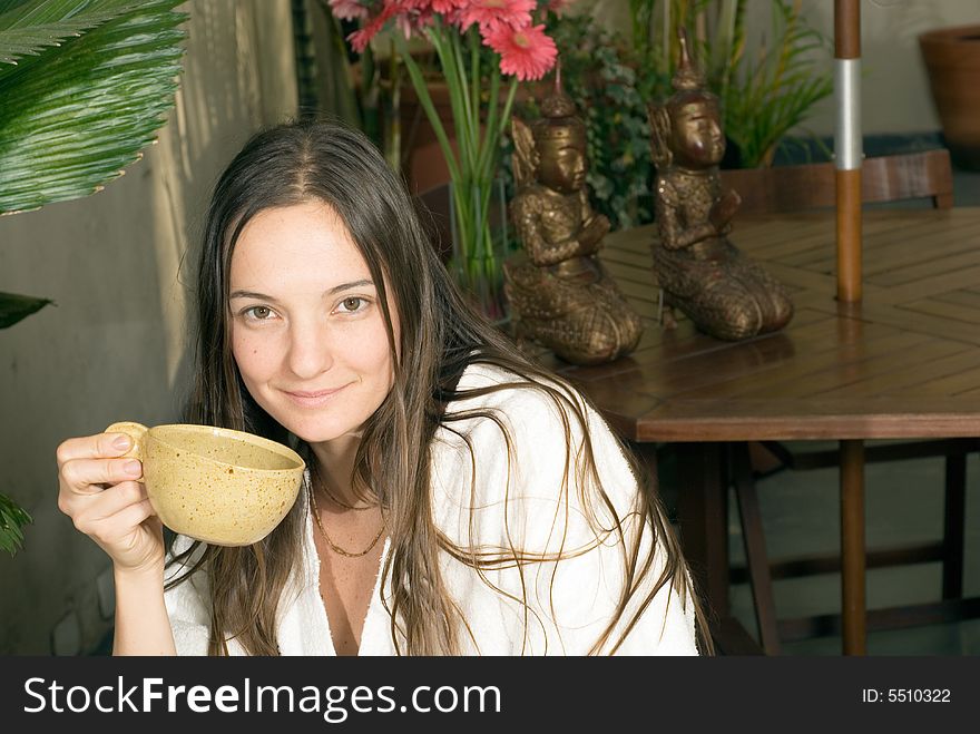 Woman smiles as she holds a tea cup. Horizontally framed photograph. Woman smiles as she holds a tea cup. Horizontally framed photograph.