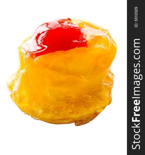 One small cake decorated with the a mango and a cherry close up on a white background. One small cake decorated with the a mango and a cherry close up on a white background