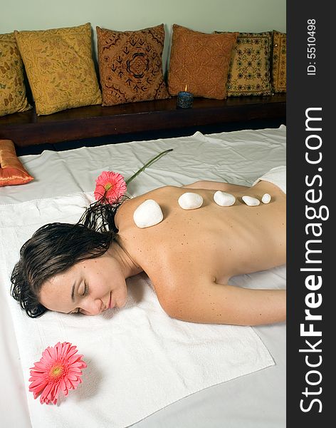 Woman closes her eyes and relaxes as she gets a hot stone massage. Vertically framed photograph. Woman closes her eyes and relaxes as she gets a hot stone massage. Vertically framed photograph.