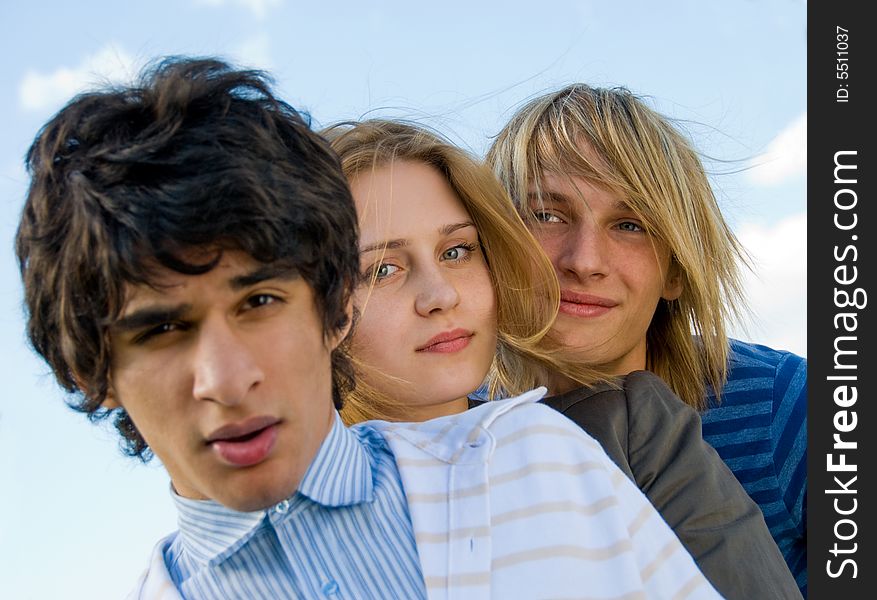 Three stylish young friends over sky background