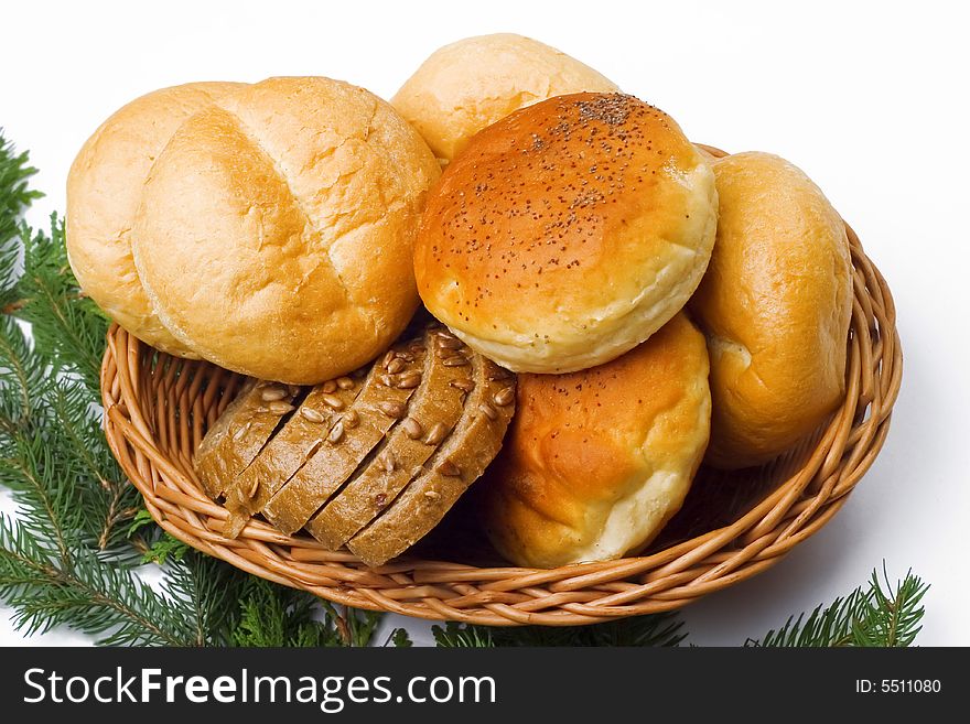 Basket full of fresh rolls and bread; pine needles as a background