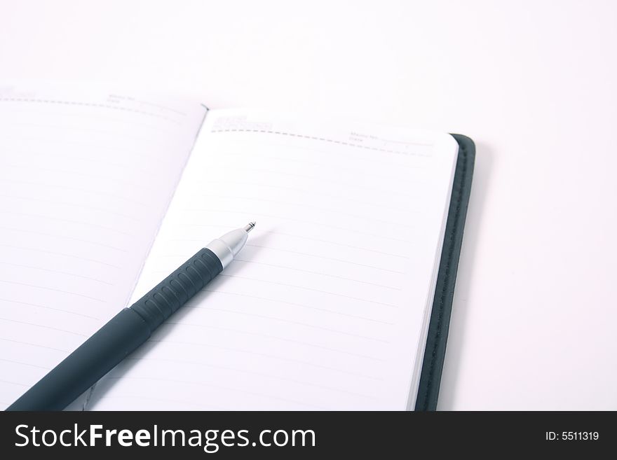 Pen on blank notebook on isolated white background.