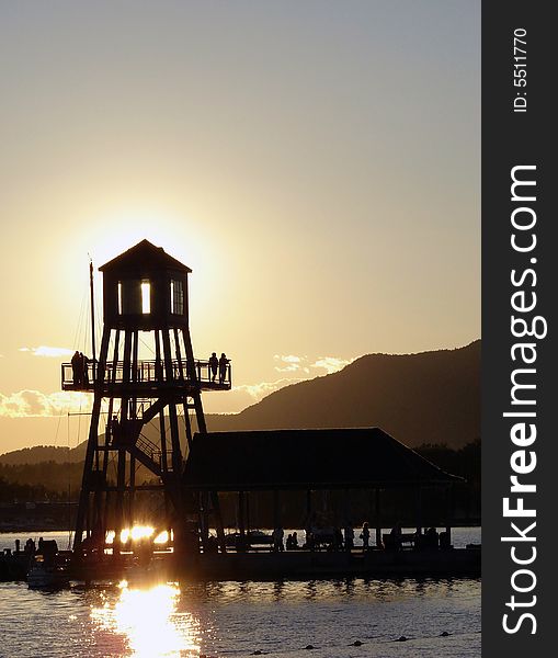 Observation tower in silhouette at sunset on Memphremagog lake, province of Quebec, Canada, with Mont-Orford in background. Observation tower in silhouette at sunset on Memphremagog lake, province of Quebec, Canada, with Mont-Orford in background
