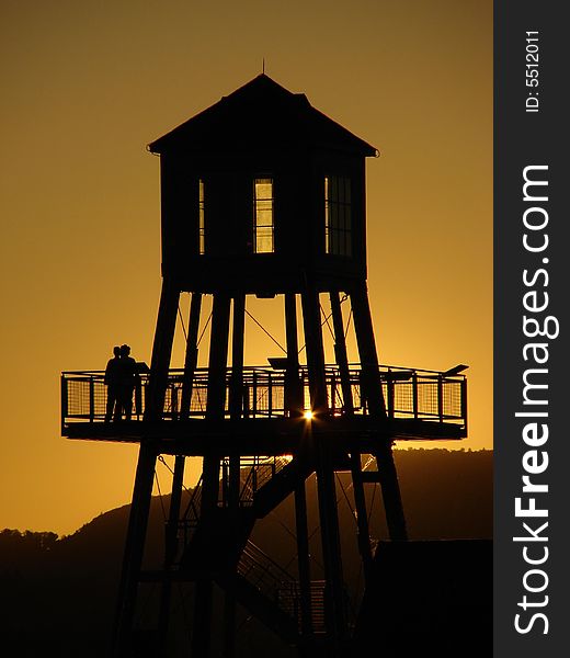 Observation tower in silhouette at sunset on Memphremagog lake in Magog, province of Quebec, Canada, with Mont-Orford in background. Observation tower in silhouette at sunset on Memphremagog lake in Magog, province of Quebec, Canada, with Mont-Orford in background