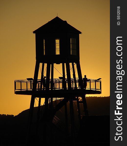 Observation tower in silhouette at sunset on Memphremagog lake in Magog, province of Quebec, Canada, with Mont-Orford in background. Observation tower in silhouette at sunset on Memphremagog lake in Magog, province of Quebec, Canada, with Mont-Orford in background