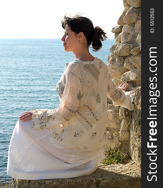 Lonely Young Woman on Stone Looking to Sea