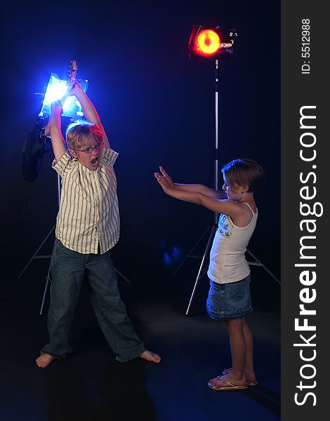 Big brother holding guitar up in the air and getting ready to smash it on his little sister, who has her hands out in defense.