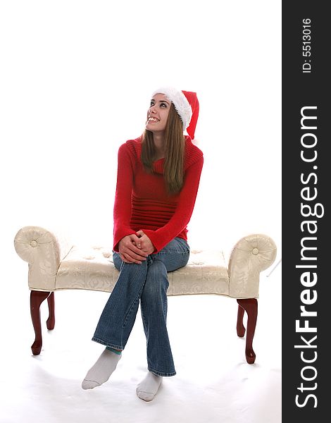 Pretty teenage girl sitting on a bench with her legs crossed and wearing a Santa Hat. Pretty teenage girl sitting on a bench with her legs crossed and wearing a Santa Hat.