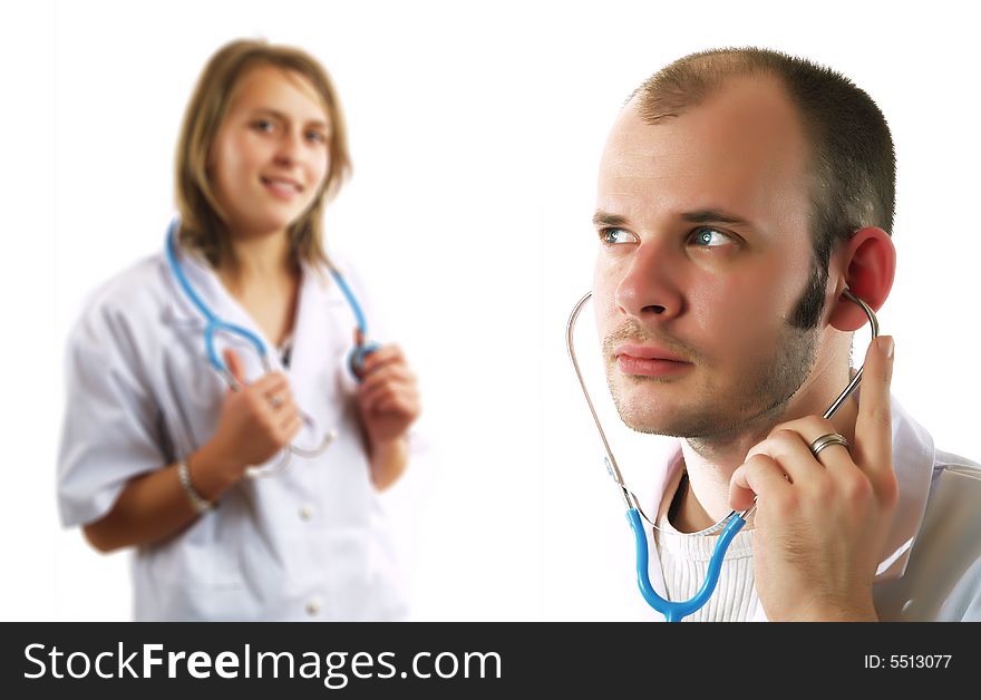An attractive doctor is listening with a stethoscope. Behind him there is his colleague pretty lady doctor who is smiling. They are wearing white coats. An attractive doctor is listening with a stethoscope. Behind him there is his colleague pretty lady doctor who is smiling. They are wearing white coats.
