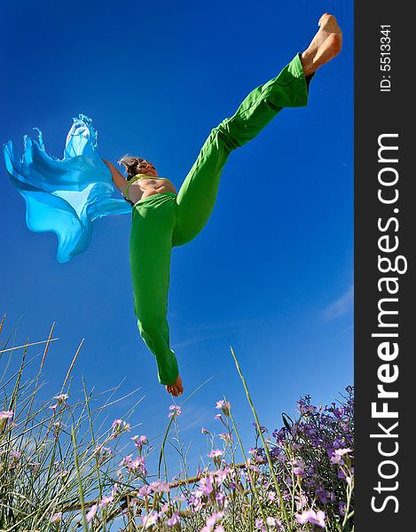 Girl with blue silk scarf jumping and the blue sky