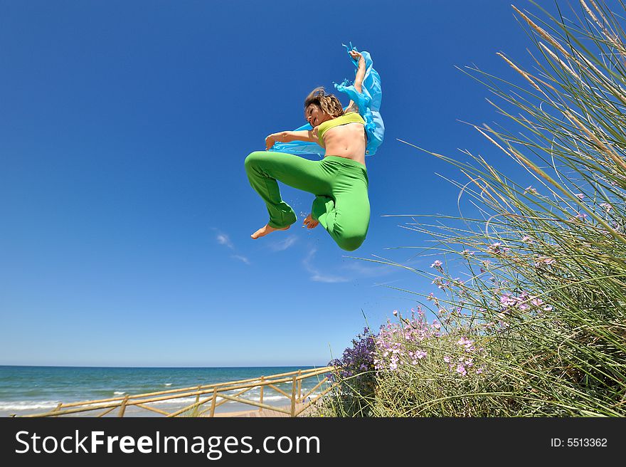 Girl with blue silk scarf jumping on the beach. Girl with blue silk scarf jumping on the beach