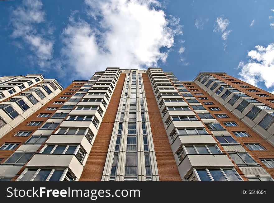 A residential multistory house and sky with clouds, view from below. A residential multistory house and sky with clouds, view from below