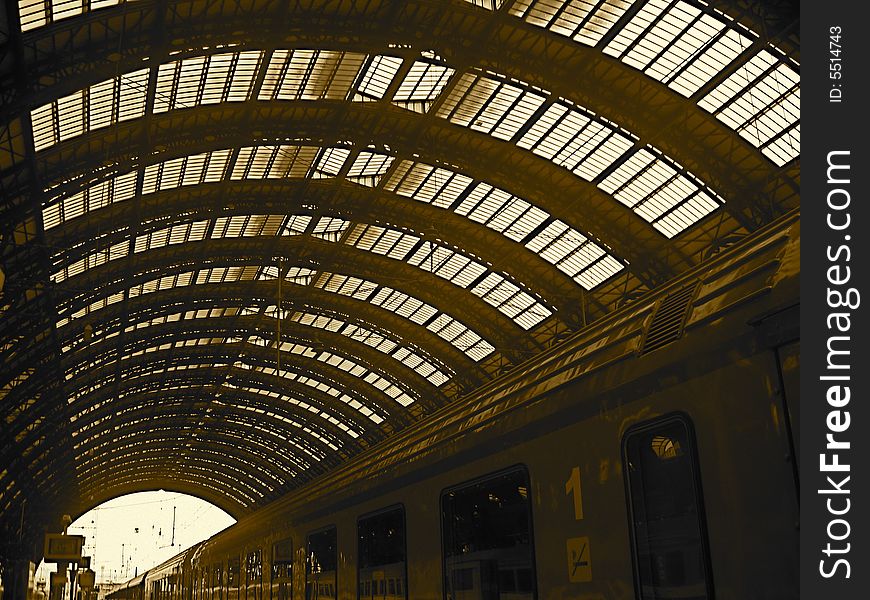 Moving train leaving Italian Train station with vaulted skylight ceiling. Shadows.