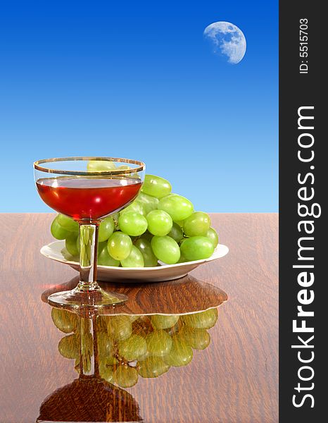 Glass with red wine, standing on a table next to cluster of vine