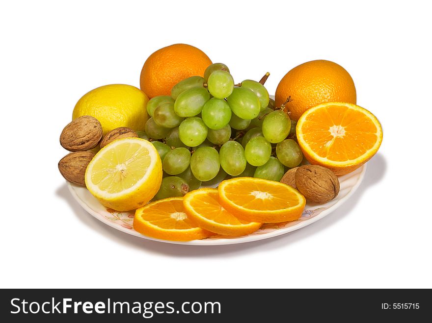 Lemons, sweet oranges, walnut and cluster of vine on a dish. Lemons, sweet oranges, walnut and cluster of vine on a dish