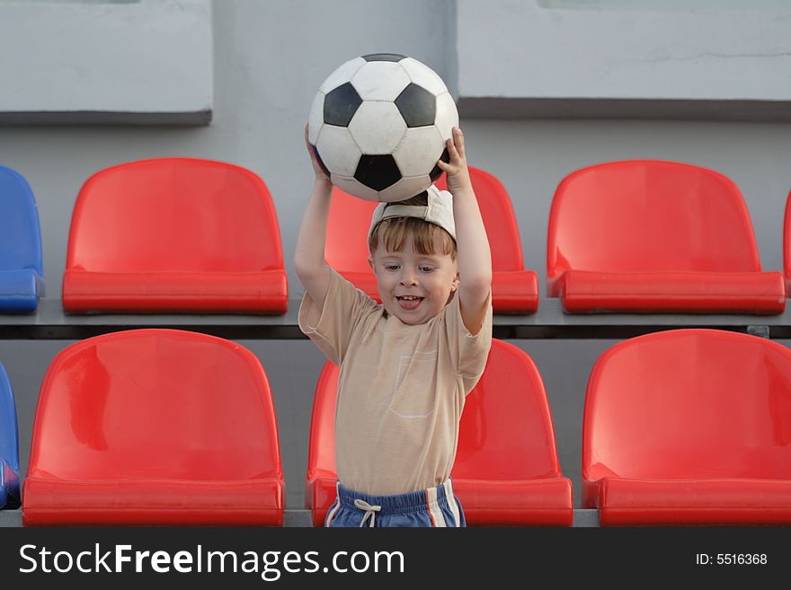 The boy with a ball on tribunes of stadium